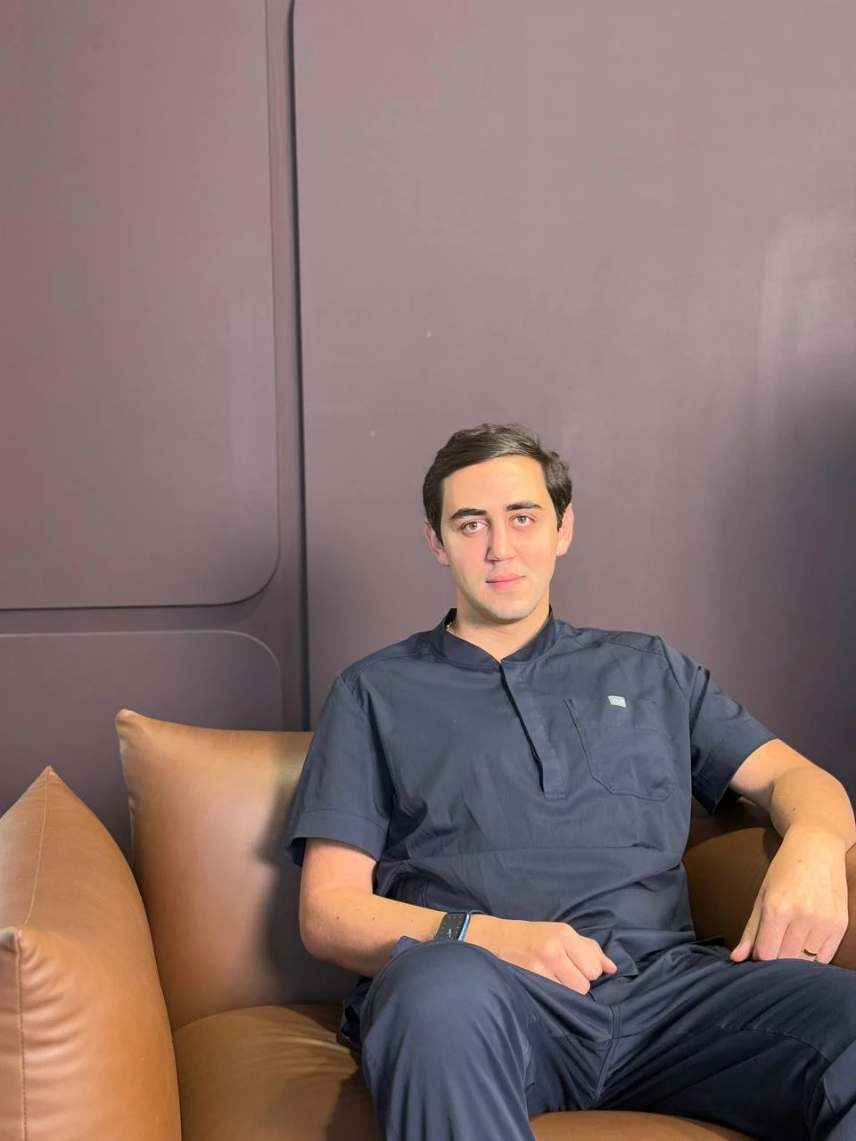 Mr. Botox in navy scrubs in a warm-toned interior