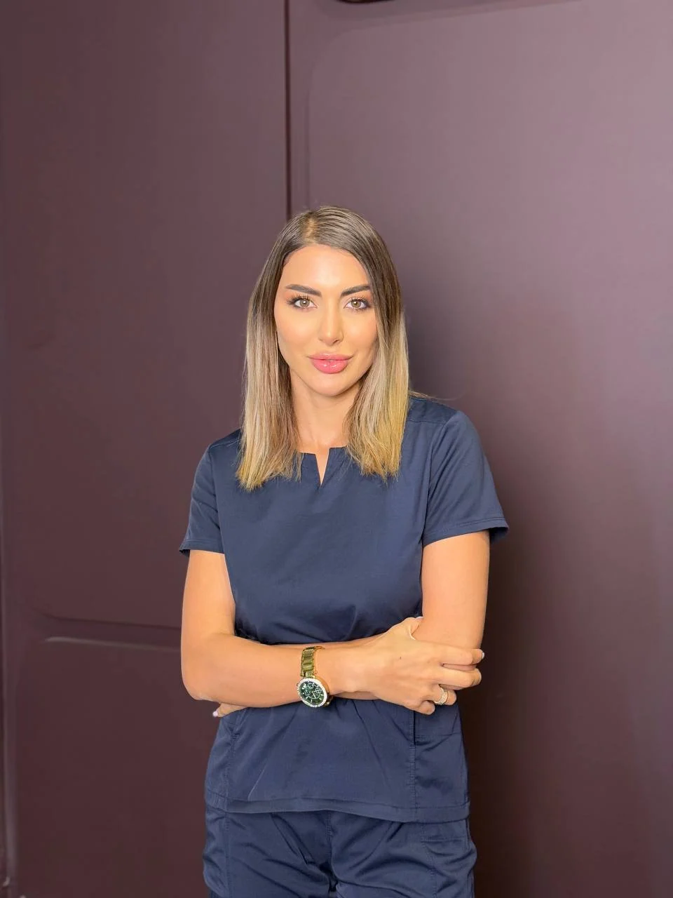 Mrs. Botox in navy scrubs against a soft mauve background